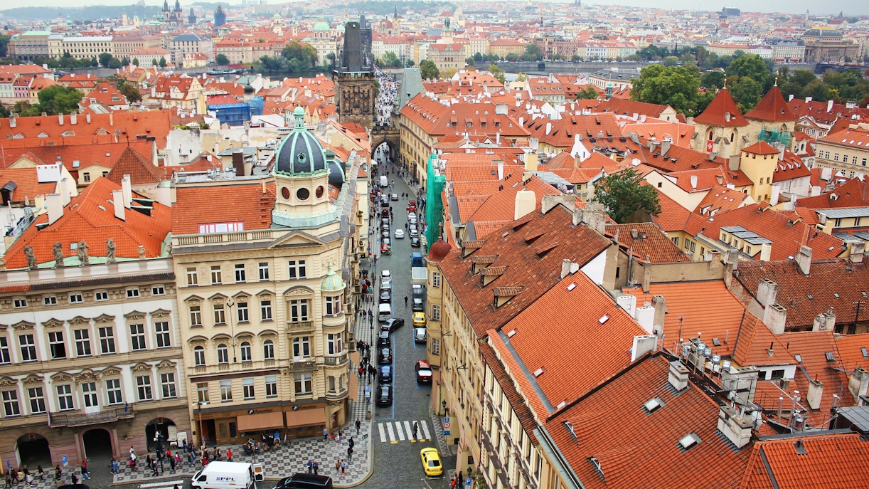 Aerial view of Mostecka street near St Nicholas Bell Tower, Prague, with red rooftops and historic buildings.