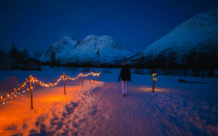 Pathway with lights in snowy Tromso Lapland, mountains in the background.