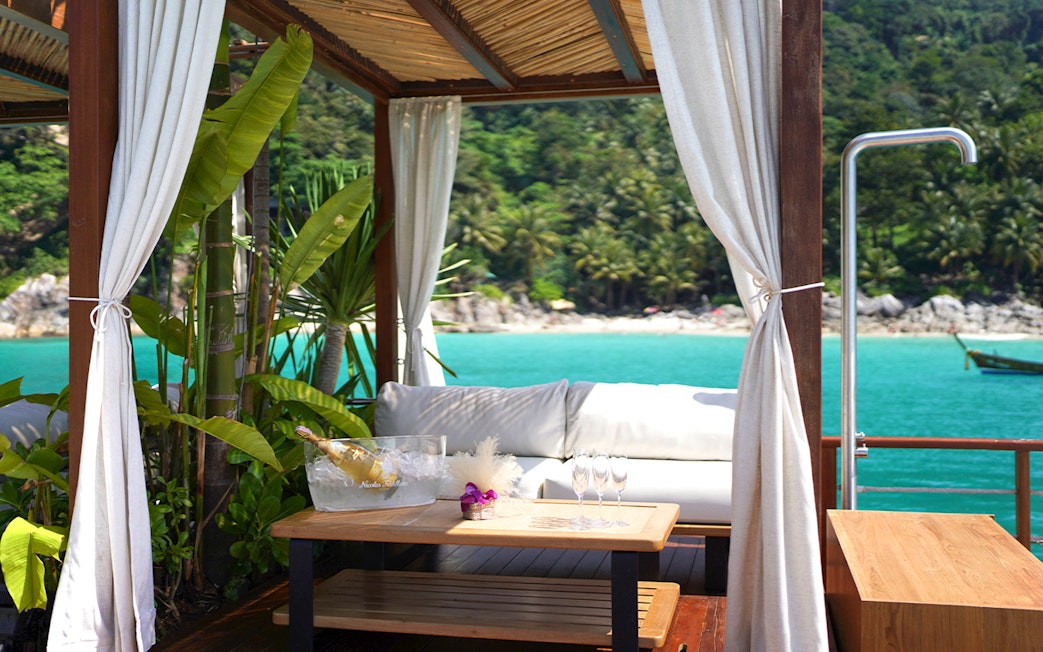 Private cabana at Yona Beach Club, Phuket, overlooking turquoise sea and lush greenery.