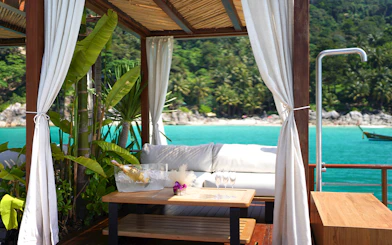 Private cabana at Yona Beach Club, Phuket, overlooking turquoise sea and lush greenery.