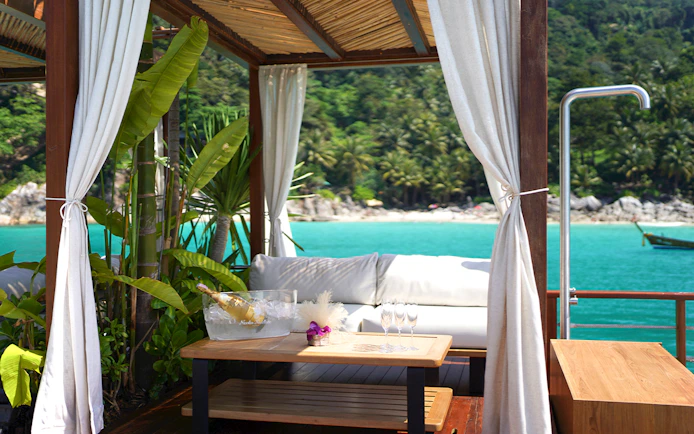 Private cabana at Yona Beach Club, Phuket, overlooking turquoise sea and lush greenery.