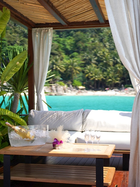 Private cabana at Yona Beach Club, Phuket, overlooking turquoise sea and lush greenery.