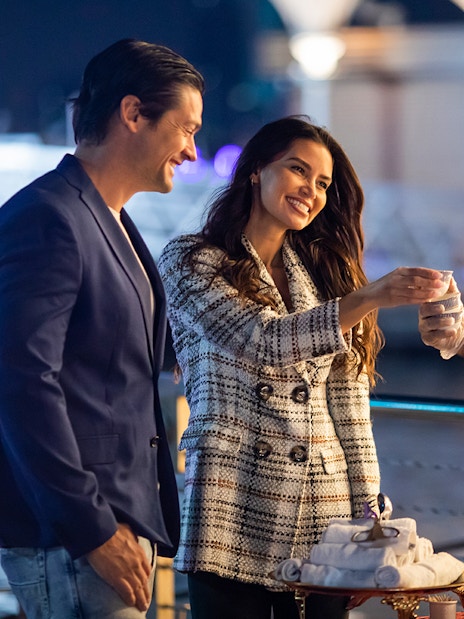 Couple enjoying a drink served by a waiter on a Dubai Canal cruise.