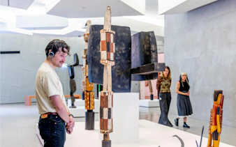 Visitor with headphones viewing indigenous art at National Gallery of Victoria.