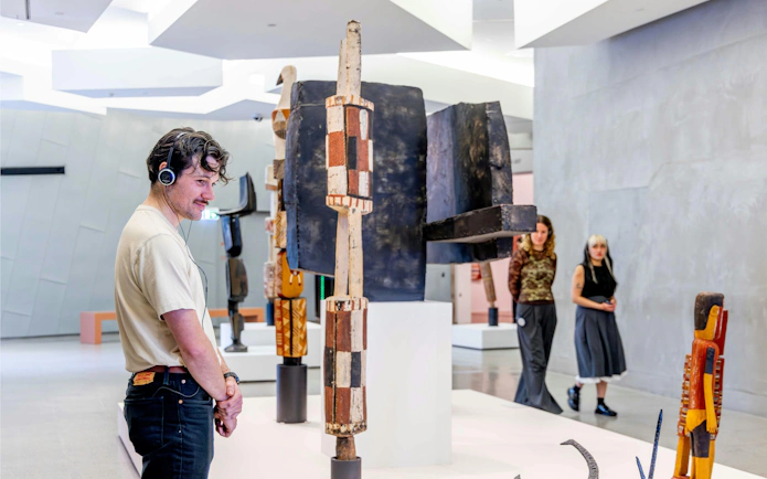 Visitor with headphones viewing indigenous art at National Gallery of Victoria.