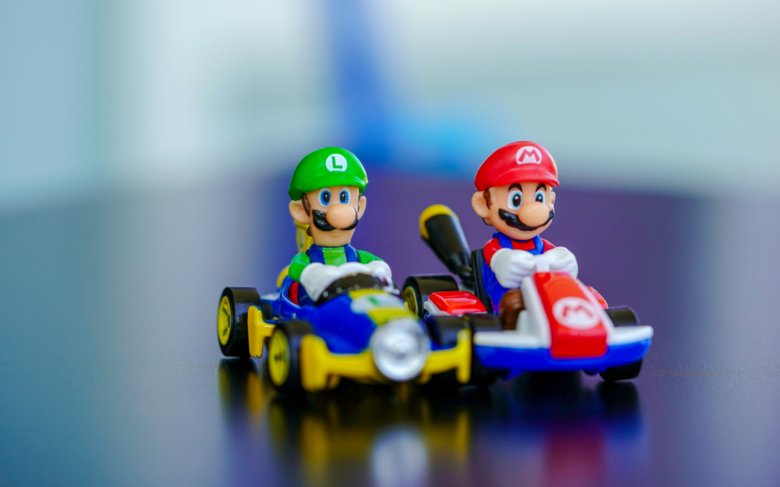 Mario Kart figurines racing on a track with colorful background.