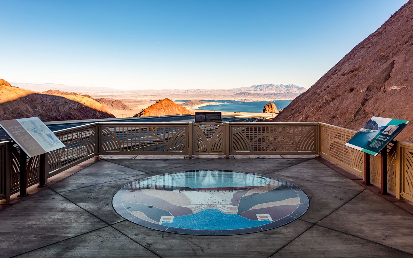 Lake Mead overlook with informational signs and distant view of the lake and mountains.