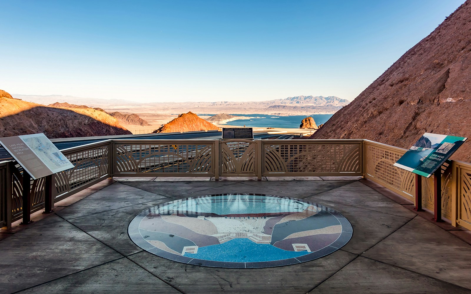 Lake Mead overlook with informational signs and distant view of the lake and mountains.