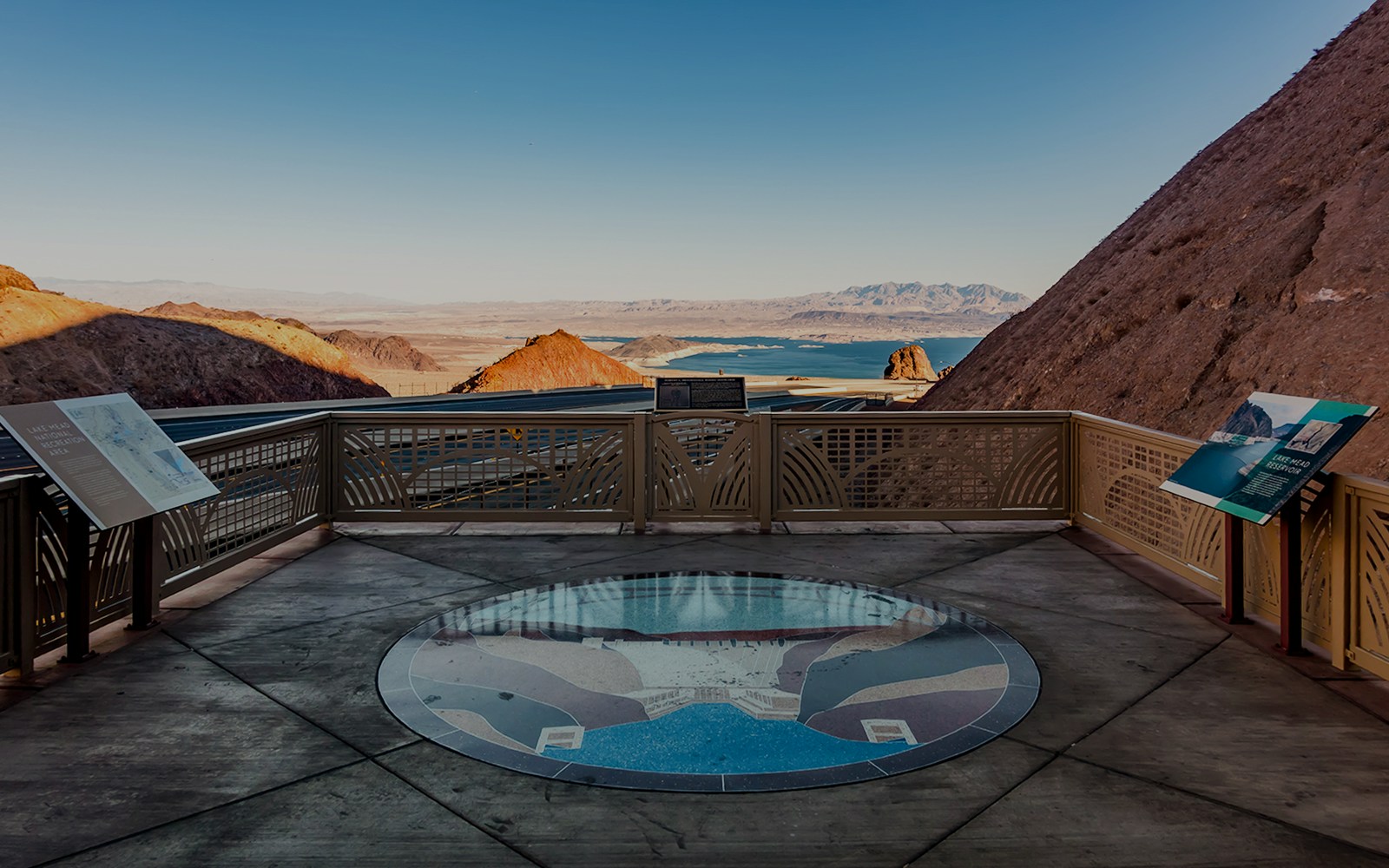 Lake Mead overlook with informational signs and distant view of the lake and mountains.