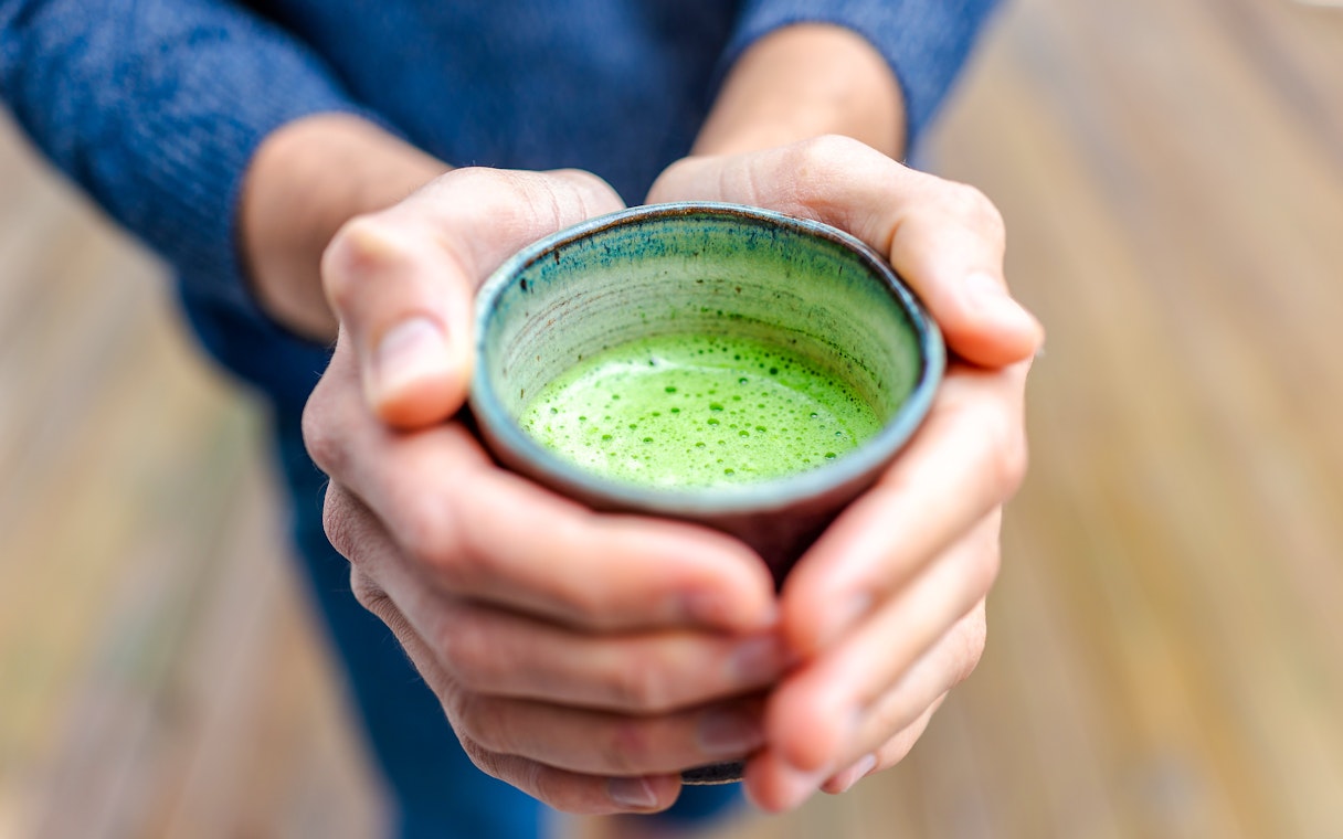 Tourist holding a cup of Matcha tea.