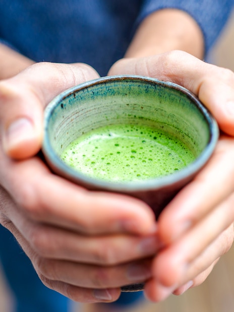 Tourist holding a cup of Matcha tea.