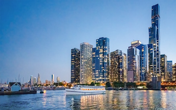 Downtown Chicago skyscrapers at sunset with a cruise boat on Lake Michigan.