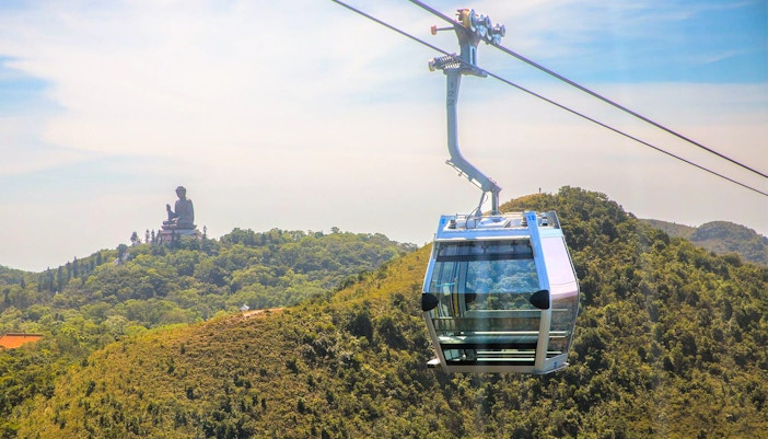 Ngong Ping Cable Car gliding over lush green hills in Hong Kong.