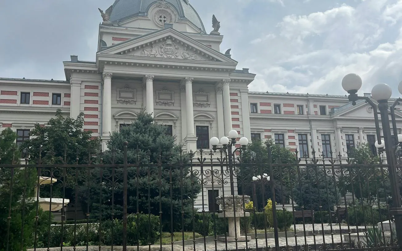 Historic building with columns and ornate facade in Bucharest, part of The Vanishing Pharmacist game.