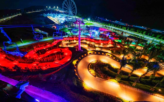 Night view of illuminated tracks and Ferris wheel at Skyline Luge Kuala Lumpur.