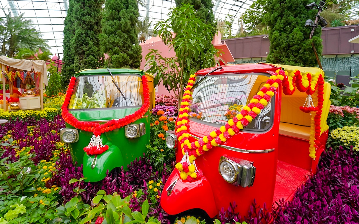 Colorful tuk-tuks adorned with garlands in Gardens by the Bay, Singapore.