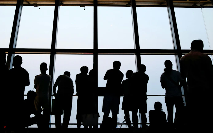 Visitors viewing skyline from observation deck window.