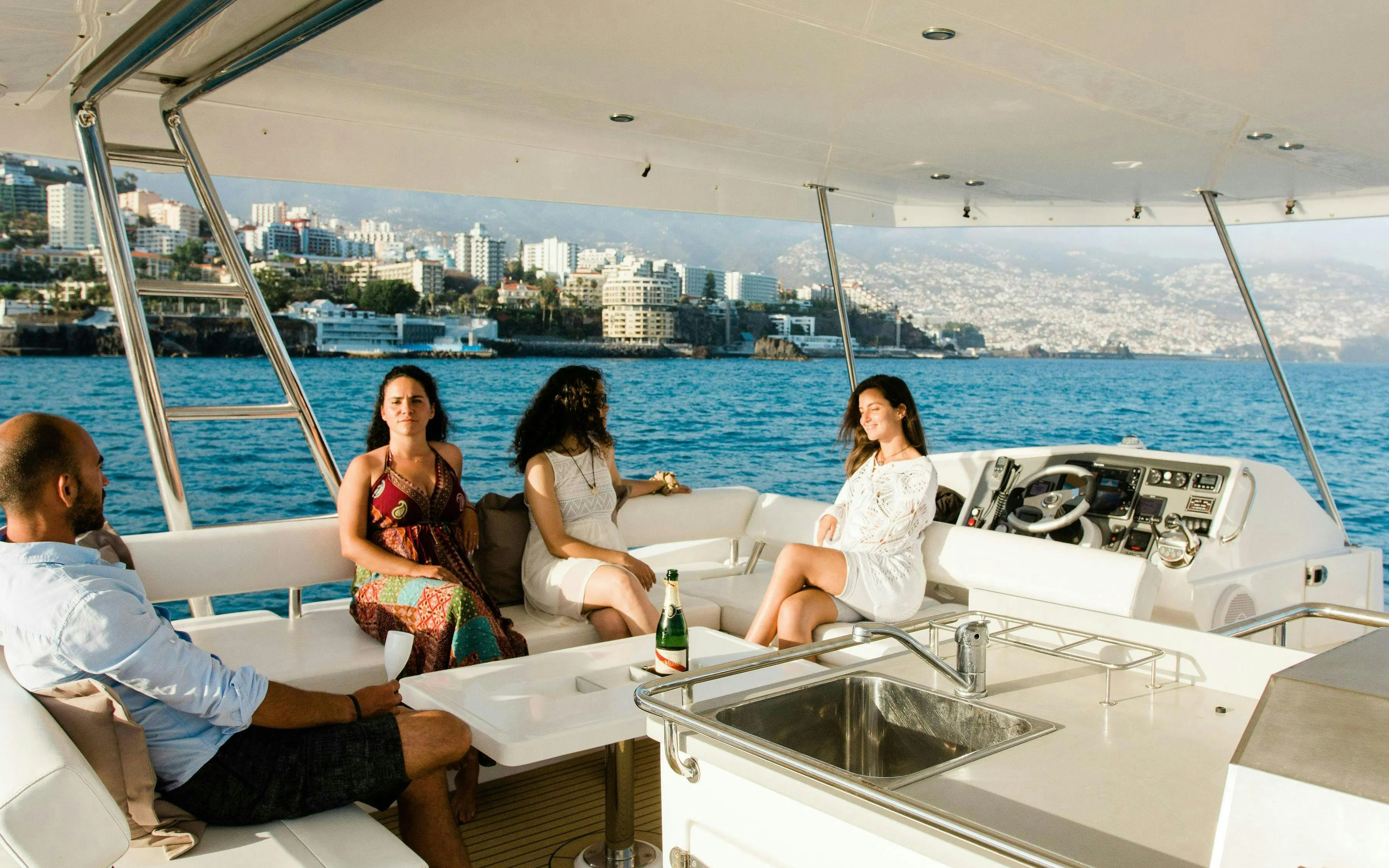 Small group relaxing on a yacht during a dolphin and whale watching cruise near a coastal city.