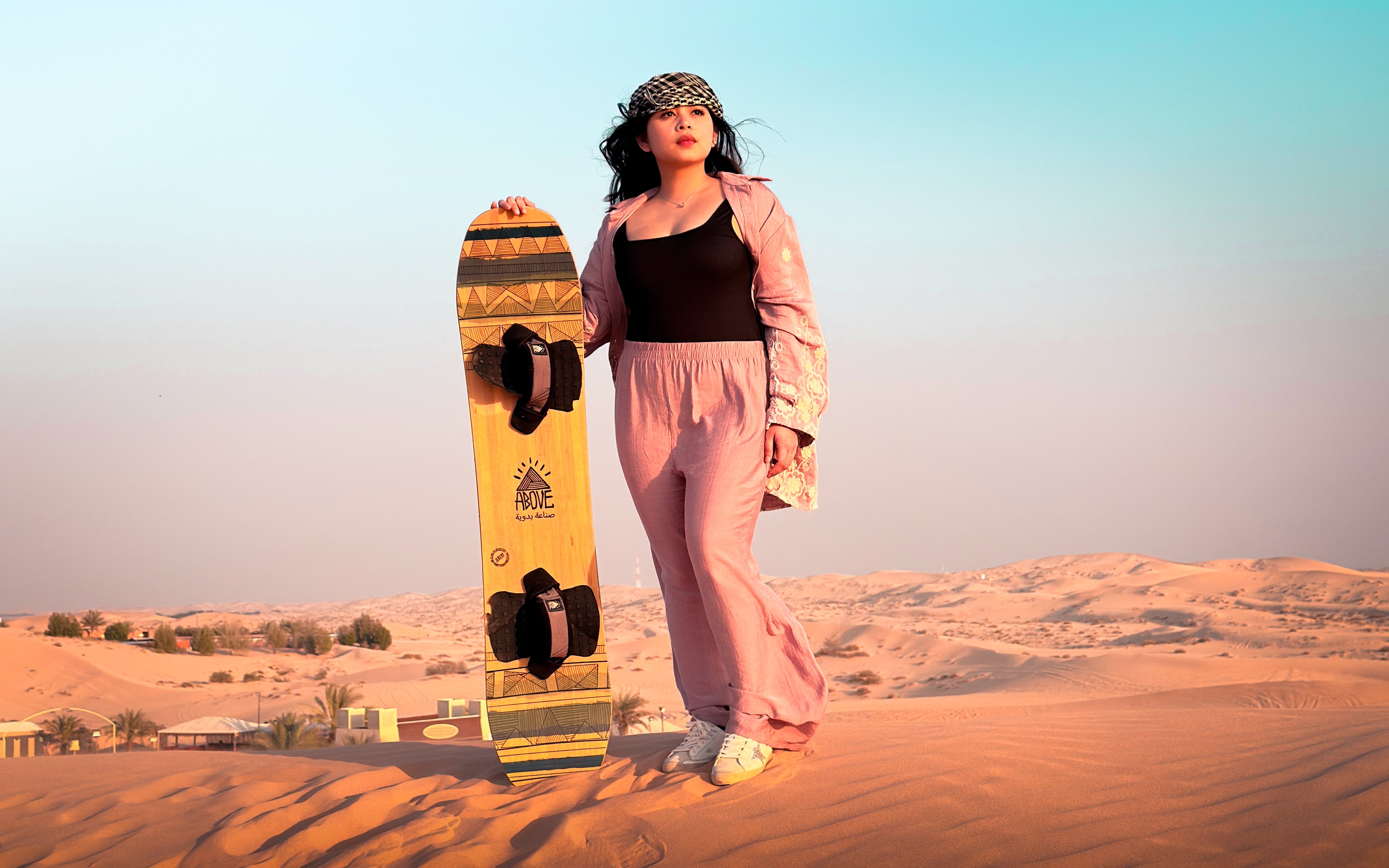 Woman with sandboard on desert safari, Abu Dhabi dunes.