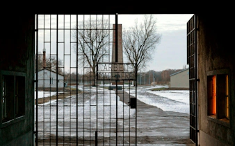 Open gate with "Arbeit Macht Frei" sign and clock tower at Sachsenhausen Concentration Camp.