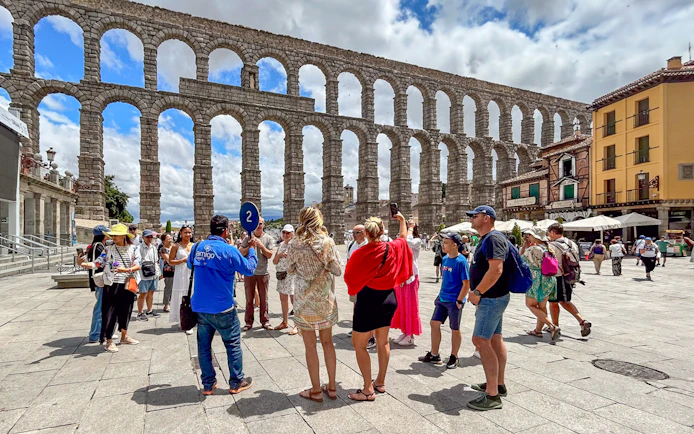 Tourists with guide at Segovia aqueduct, Spain.