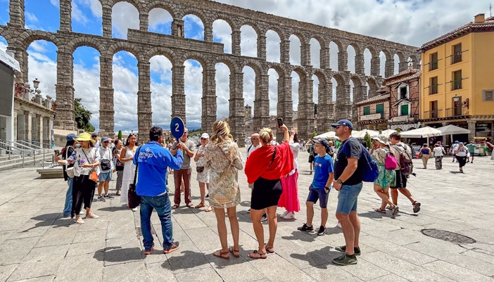 Tourists with guide at Segovia's Roman aqueduct, Spain.