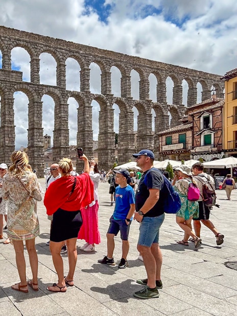 Tourists with guide at Segovia aqueduct, Spain.