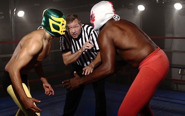 Wrestlers in colorful masks face off in a Mexico City ring during a guided night tour.