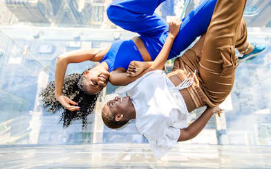 Two people lying on the glass floor of the Skydeck at Willis Tower, Chicago.
