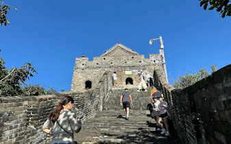 Visitors climbing steps at Mutianyu Great Wall, Beijing, with watchtower in view.