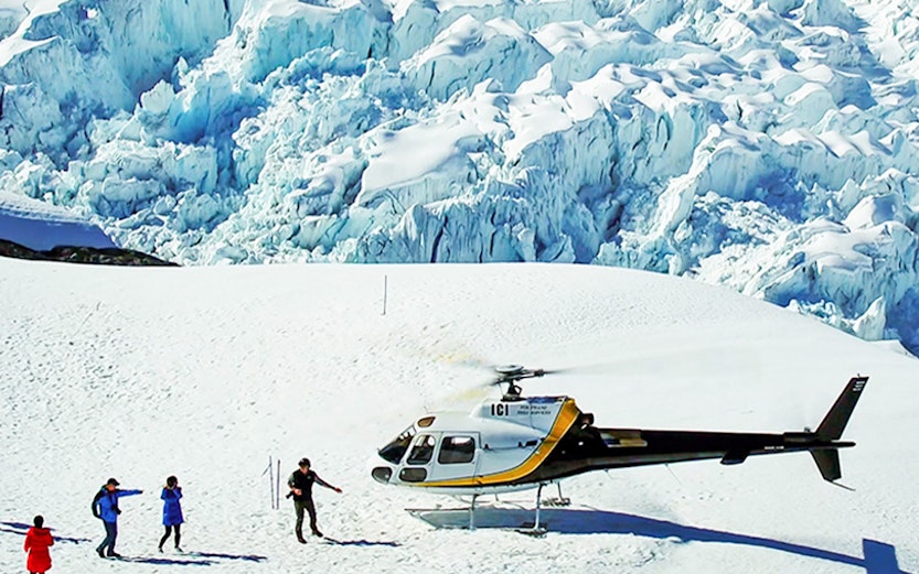 Helicopter landing on Franz Josef Glacier with hikers nearby.