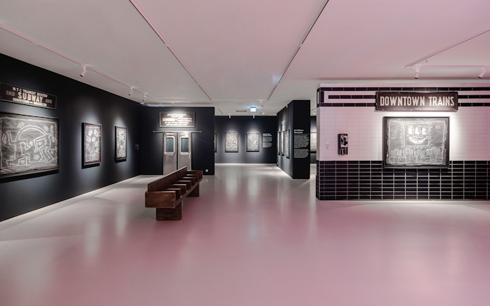 Keith Haring artworks in subway-themed room at Moco Museum London exhibit.