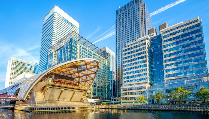 Thames cruise boat passing Canary Wharf skyscrapers on the Isle of Dogs, London.