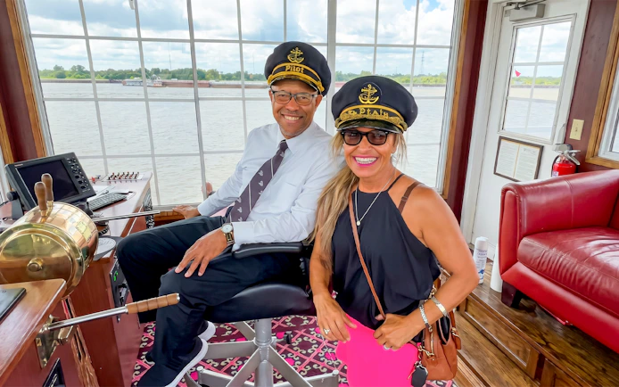 Pilot and guest in captain's hats on Riverboat City of New Orleans cruise.