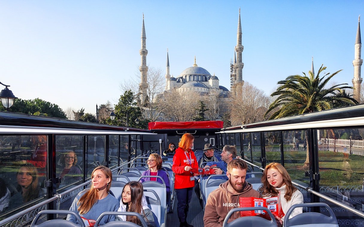 Tourists on a bus tour in Istanbul with the Blue Mosque in the background.