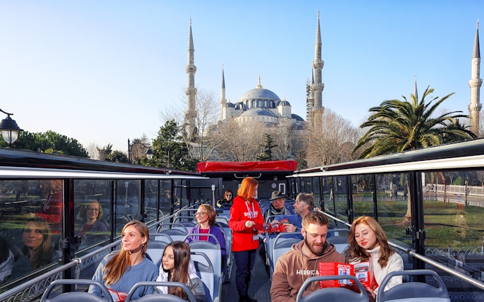 Tourists on a bus tour in Istanbul with the Blue Mosque in the background.
