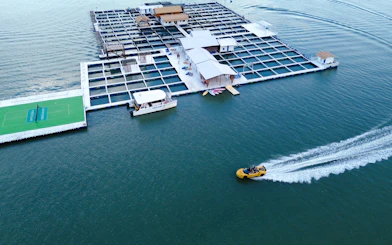 Floating platform with tennis court and boats on water, Penang catamaran cruise activities.
