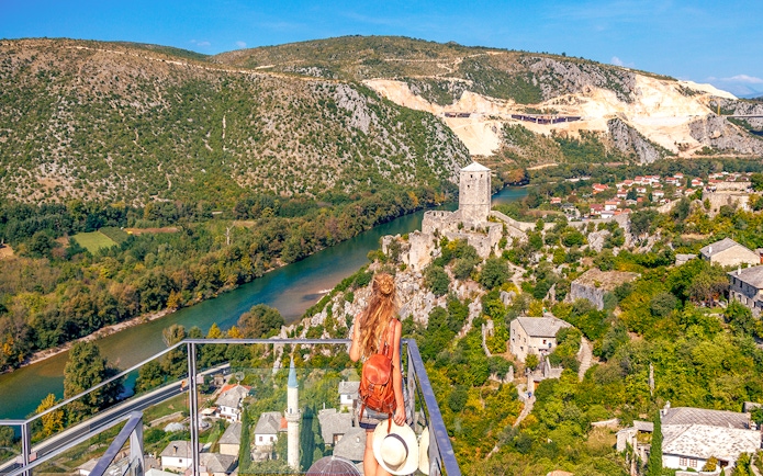 Guests overlooking Pocitelj village and river in Bosnia from a scenic viewpoint.