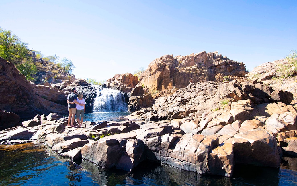 Couple standing on rocks overlooking waterfall at Katherine Gorge, Australia.