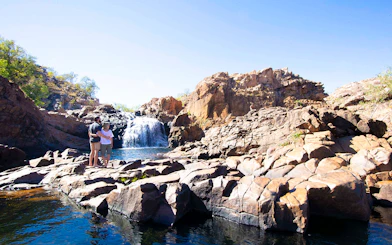 Couple standing on rocks overlooking waterfall at Katherine Gorge, Australia.