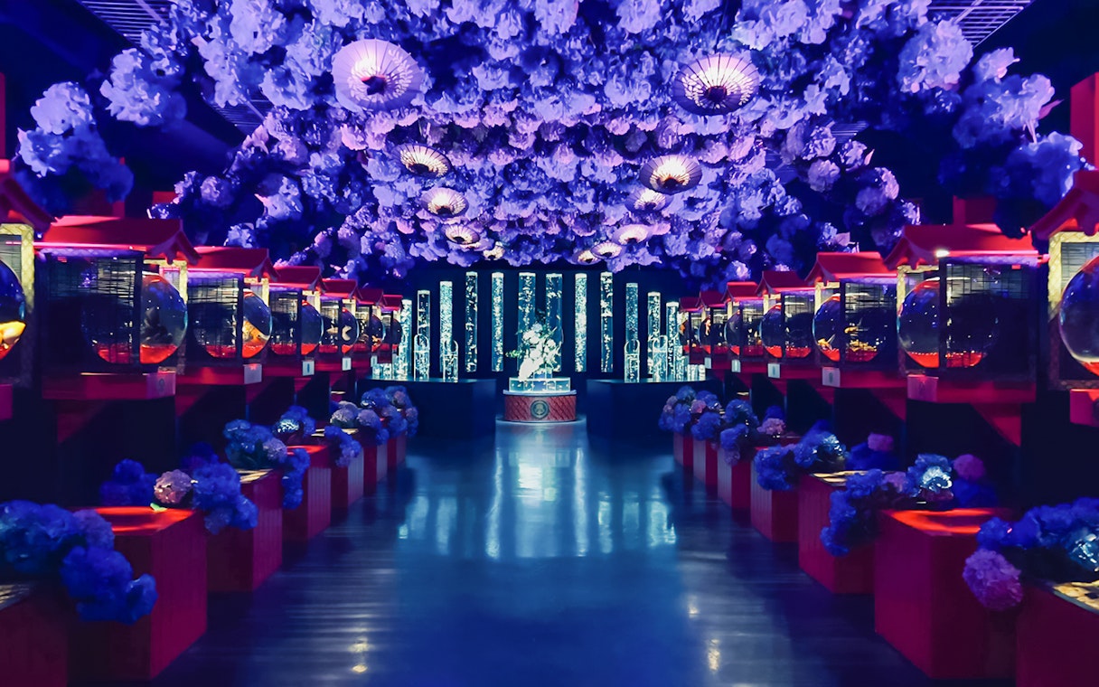 Wide view of illuminated Art Aquarium Museum GINZA with vibrant displays and floral ceiling.