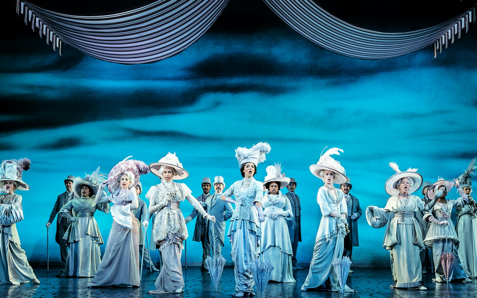 Performers in Edwardian costumes on stage during "My Fair Lady" musical.