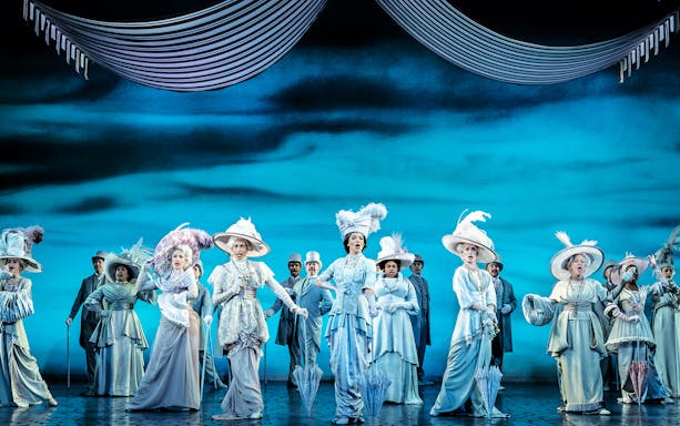 Performers in Edwardian costumes on stage during "My Fair Lady" musical.