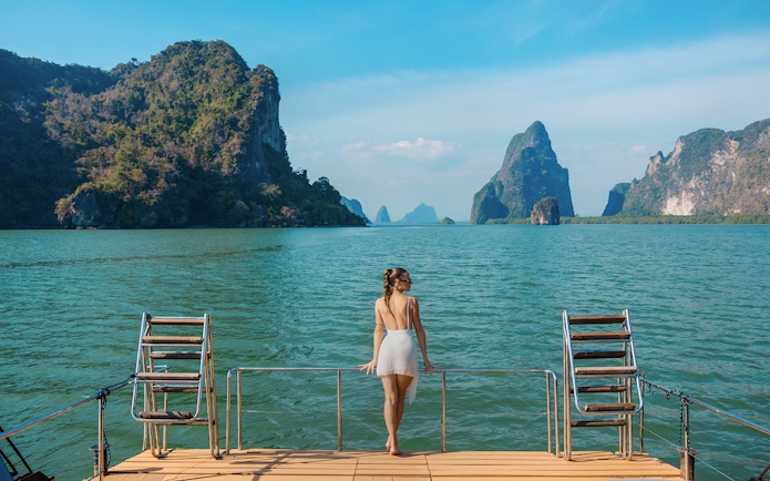 Tourist enjoying view from cruise deck in Phang Nga Bay, Thailand.