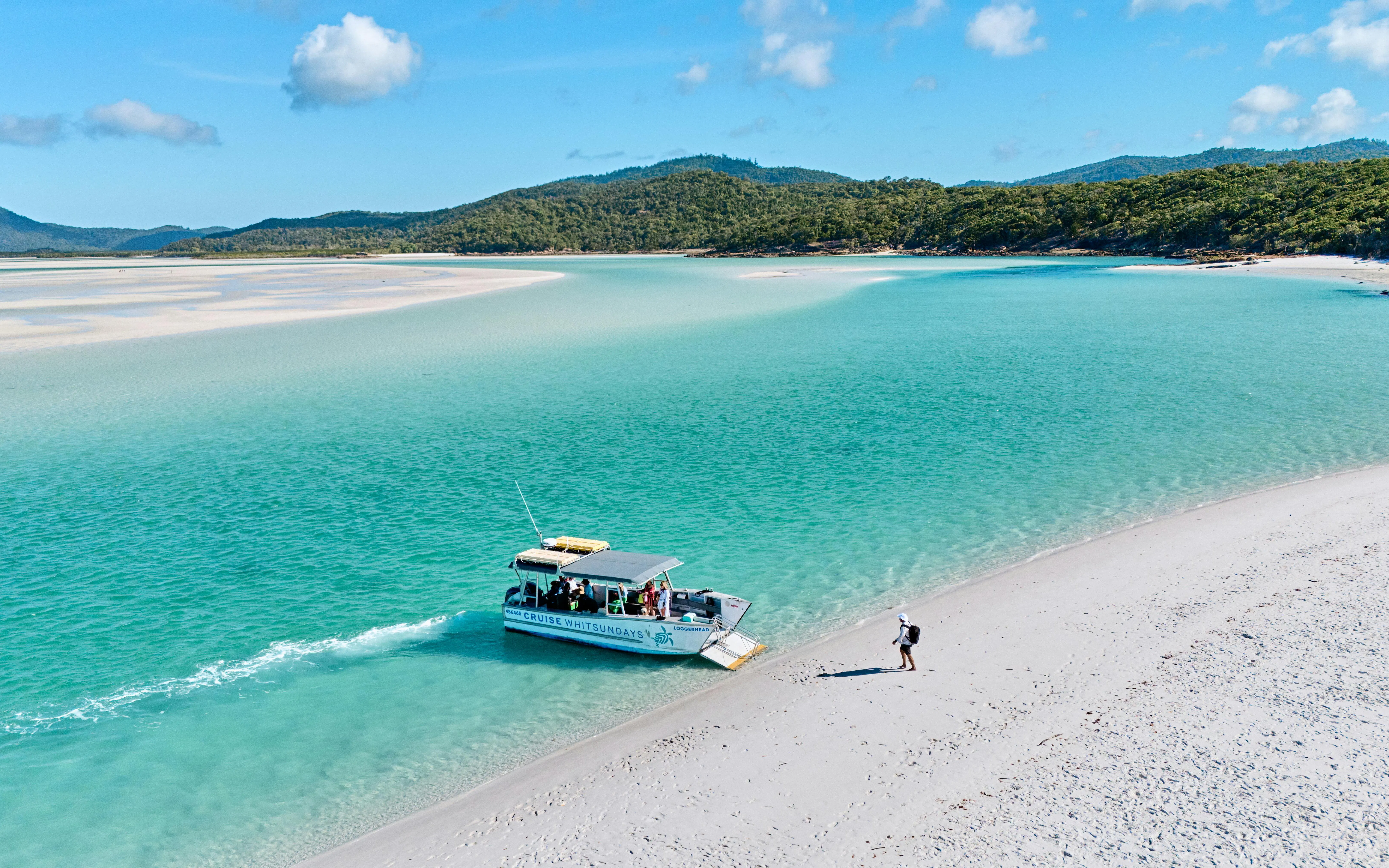 Boat arriving at Whitehaven Beach with a person walking on the sand, Whitsundays Island.