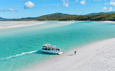 Boat arriving at Whitehaven Beach with a person walking on the sand, Whitsundays Island.