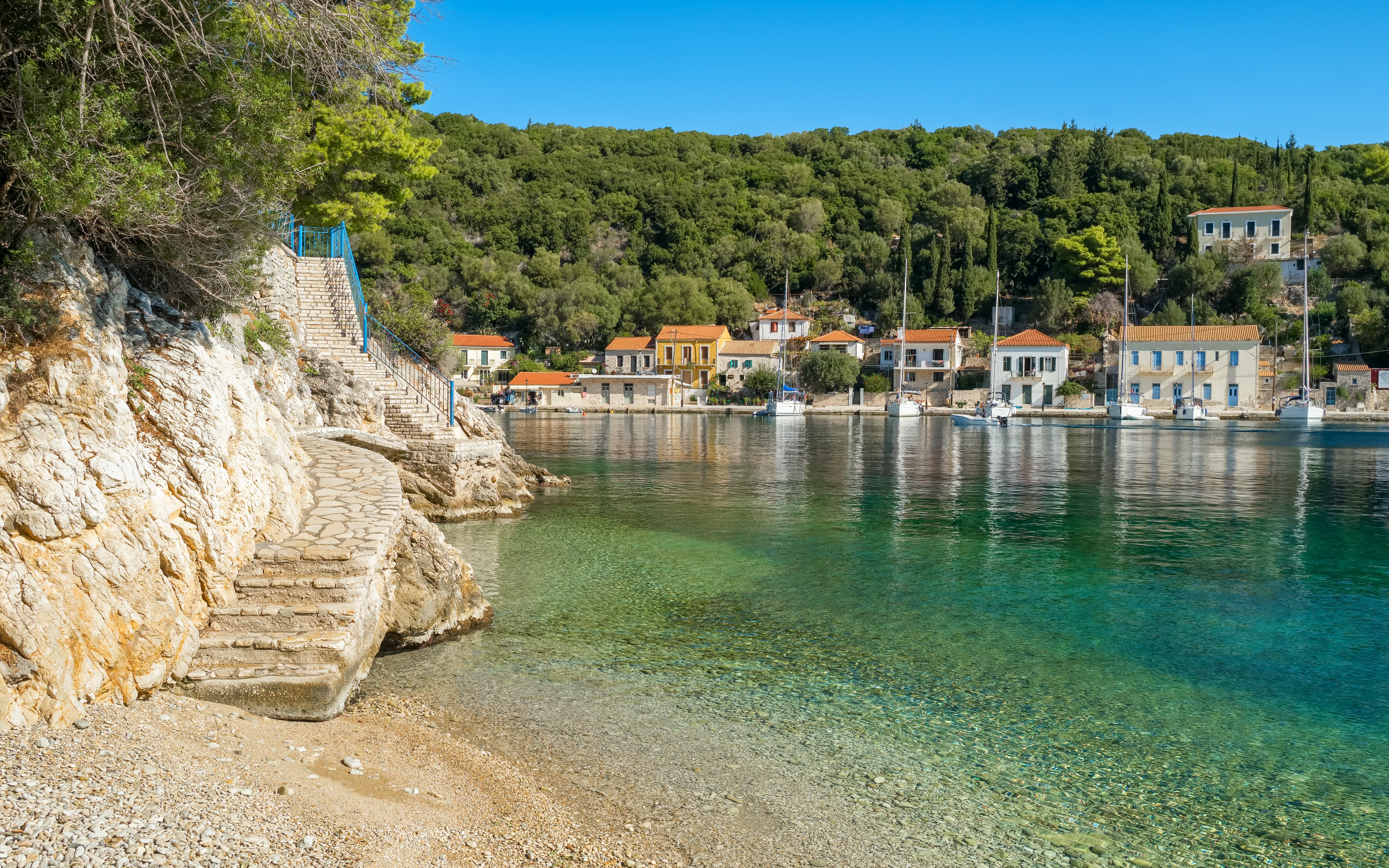 Stone steps leading to Kioni fishing village, Ithaca island, Greece, with boats and waterfront houses.