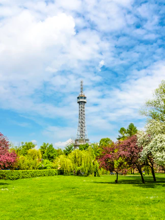 Petrin Tower in Prague surrounded by lush gardens and colorful trees.