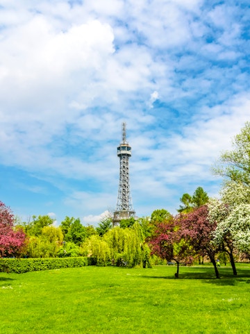 Petrin Tower in Prague surrounded by lush gardens and colorful trees.