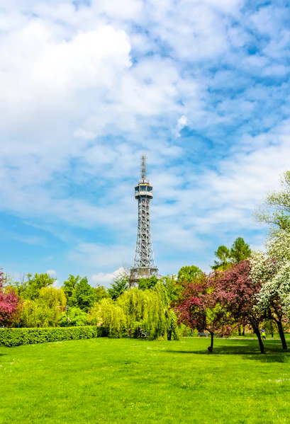 Petrin Tower in Prague surrounded by lush gardens and colorful trees.